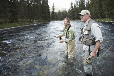 Senior man teaching woman fly-fishing