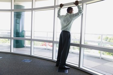 Rear view of a businessman leaning against a window frame