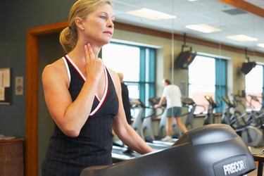 Woman checking her pulse on treadmill at gym