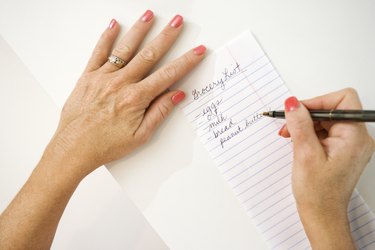 Hands writing grocery list