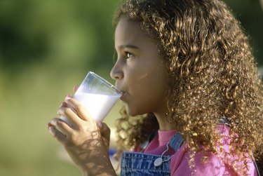 Side profile of a girl holding a glass of milk