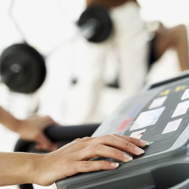 close-up of the hand of a woman selecting an exercise program on a treadmill