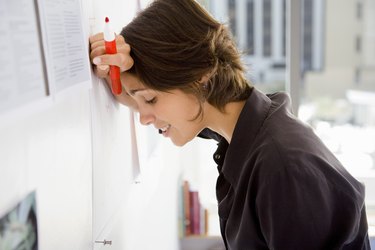 Businesswoman with marker leaning head against wall