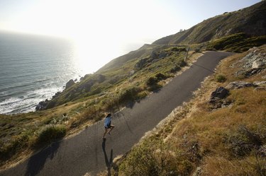 Woman jogging on road beside ocean,  California,  USA