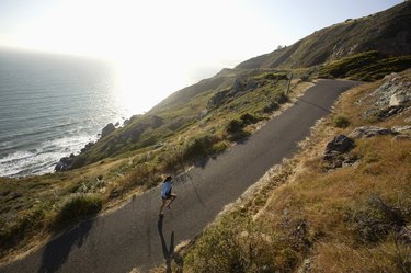 女人慢跑在道路旁的海洋,加州,美国