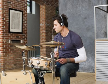 Man playing drums while wearing headphones