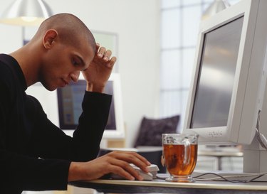 Thoughtful man using computer at Internet cafe, side view