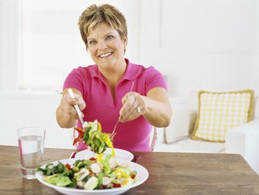 mature woman serving salad with a fork