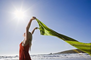 Woman with fabric fluttering on beach