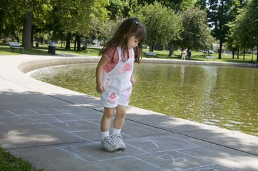 Girl playing hopscotch by pond