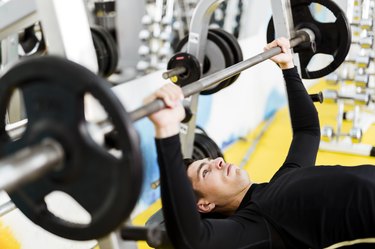 Young handsome man doing exercises on a bench press