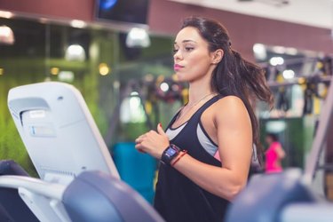 Fit women doing cardio exercises, running on treadmills in the gym