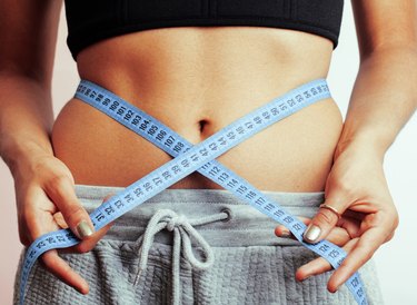 woman measuring waist with tape on knot like a gift