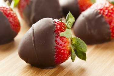 A closeup of a milk chocolate covered strawberry on a wooden surface