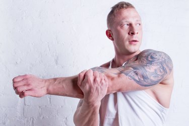 Young man with tattoos stretching arm