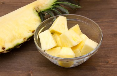 Pineapple cubes on bowl on wood