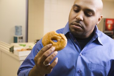 Mixed race businessman eating donut in office