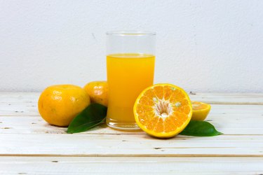 Glass of orange juice and slices of orange on wooden
