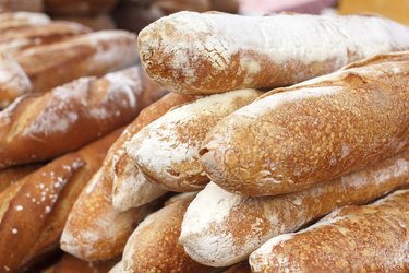 Many loaves of bread stacked in a market environment.