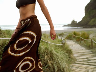 Woman walking up steps on beach (mid-section)