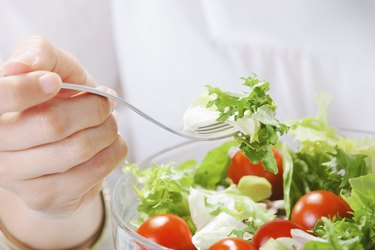 Closeup of woman eating a salad in office.