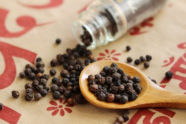 Black pepper seeds spills out of bottle