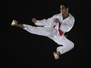 Young man practicing martial arts, jumping in midair