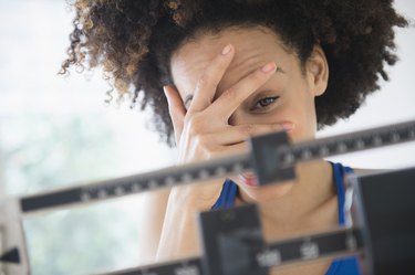 Mixed race woman hiding from weight on scale