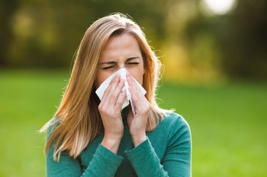 Woman with allergy symptom blowing nose