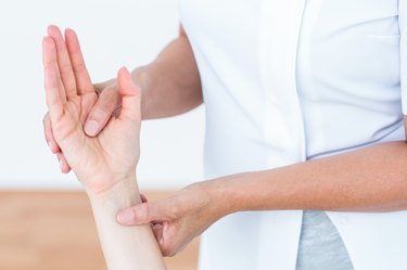 Physiotherapist examining her patients hand