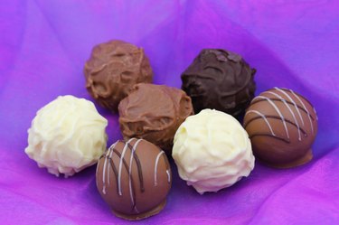 Assorted chocolates, pralines and truffles on purple background