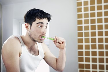 man brushing teeth in bathroom
