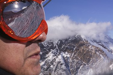 肖像的男性滑雪者在护目镜俯瞰白雪覆盖的山脉