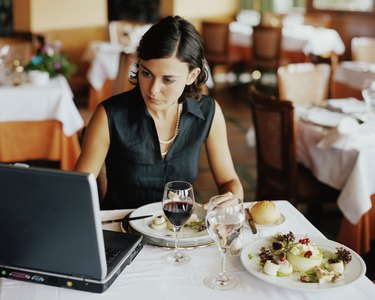 Businesswoman using laptop at restaurant table