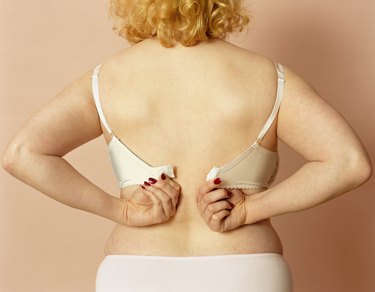 Young woman putting on bra, mid section, rear view