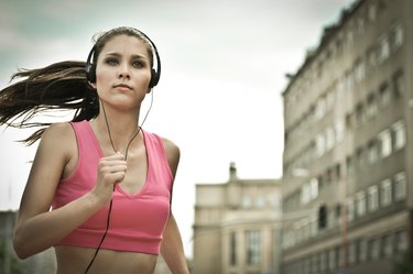 Young person listening misic running in city street