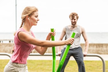 Man and woman exercising on elliptical trainer.