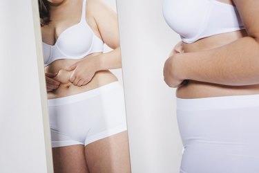 Germany, Cologne, Young woman holding her stomach