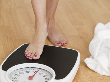 Young woman stepping on a weighing scale