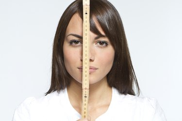 woman holding tape measure in front of face