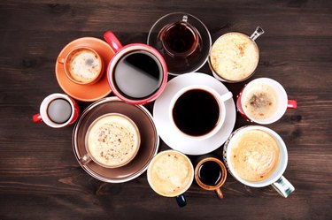 Many different cups of coffee on dark wooden table, top view.