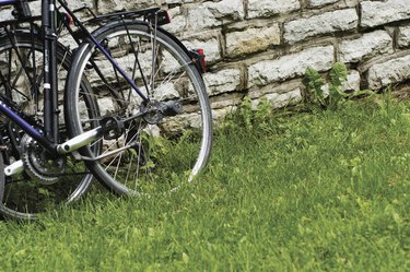 Close-up of bicycle parked on the grass against a brick wall