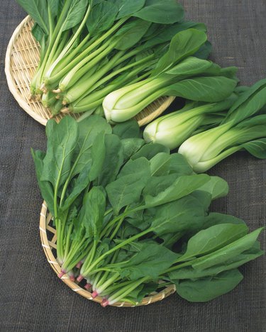Image of Spinach and Chingensai Lying on a Wooden Plate, High Angle View