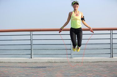 young fitness woman jumping rope at  seaside