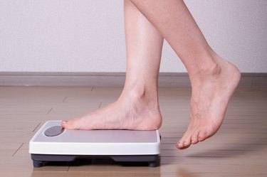 A woman's feet stepping onto a bathroom scale