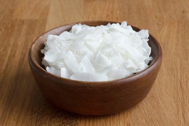 Dark bowl of shaved coconut on wood table.