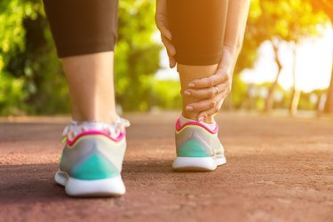 Person massaging swollen ankle from heat edema in summer