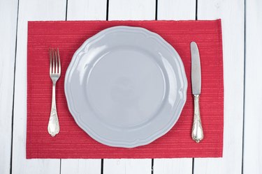 Empty Grey Plate on a red placemats with silverware