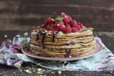 Stack of freshly baked pancakes with chocolate sauce and raspberry