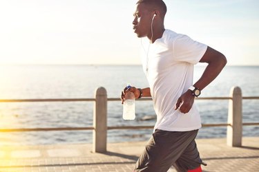 Young black male jogging next to the ocean.